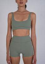 Person wearing a green sports bra and shorts set on a plain background