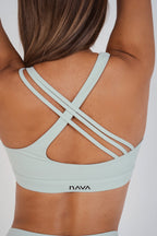 Light blue sports bra with criss-cross straps worn by a person on a white background