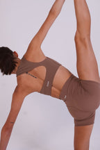 Person wearing a brown sports bra and shorts set on a white background