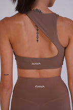 Person wearing a brown sports bra and leggings with 'NAVA' branding on a plain background