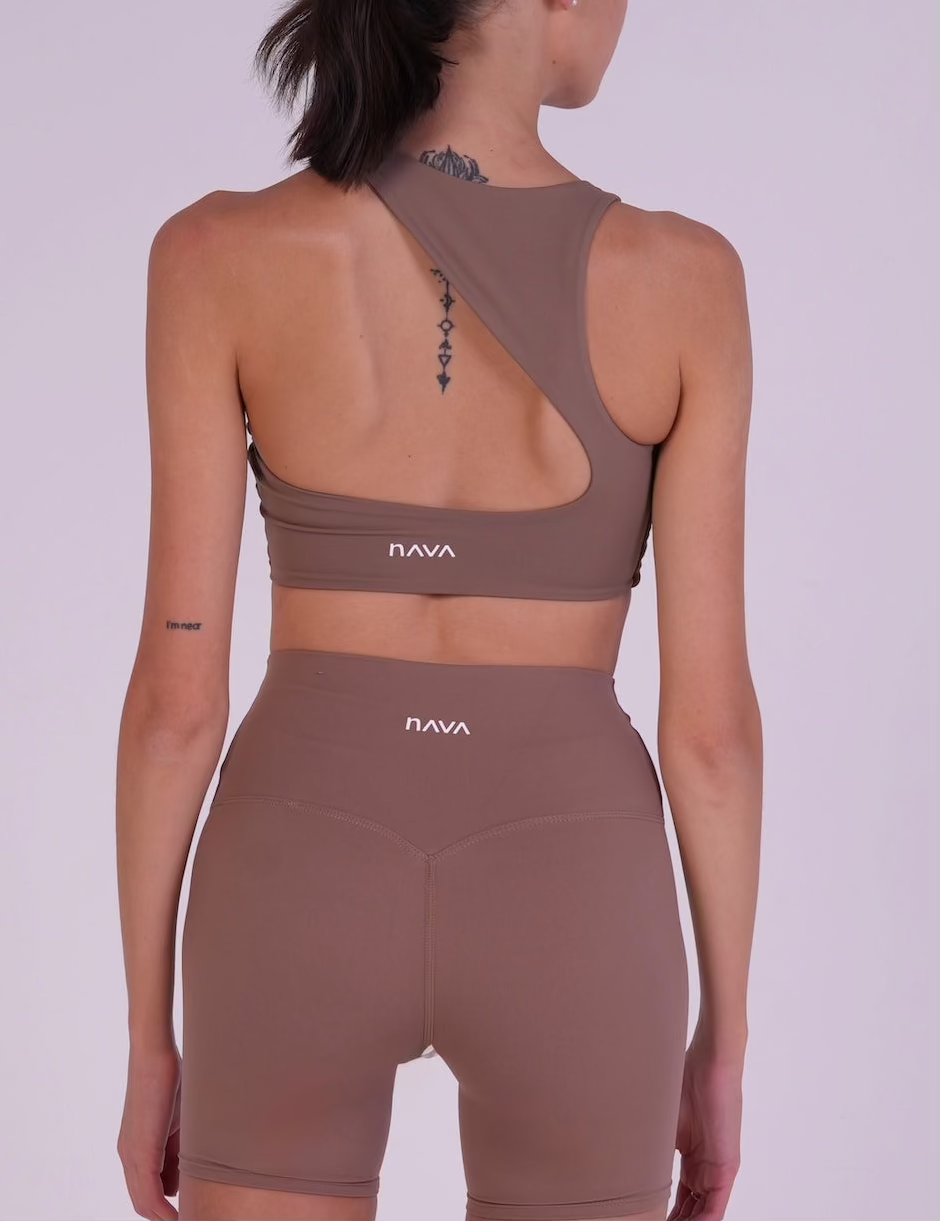 Model wearing NAVA Caramel Jasper brown activewear set, back view showing open-back top and matching high-waist shorts