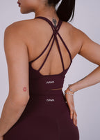 Person wearing a maroon sports bra and leggings with 'NAVA' branding on a plain background