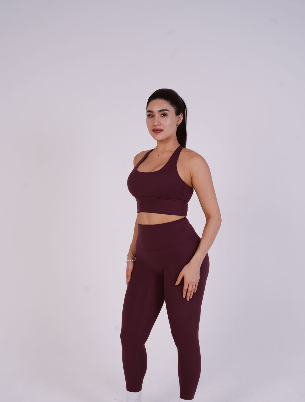 Woman wearing a maroon athletic outfit on a white background