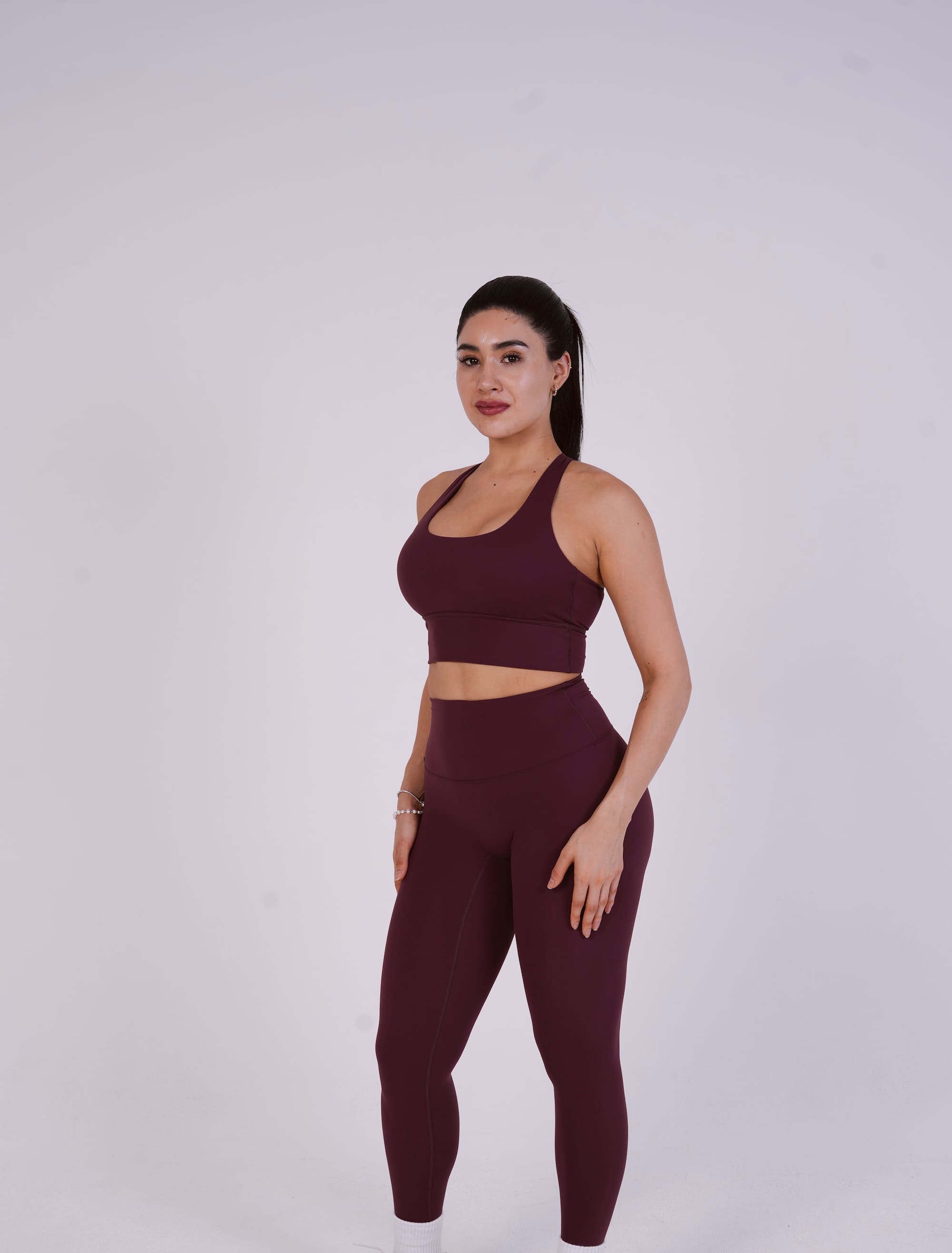 Woman wearing a maroon athletic outfit on a white background