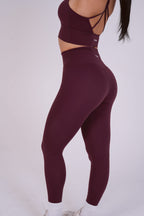 Maroon athletic leggings worn by a person on a white background