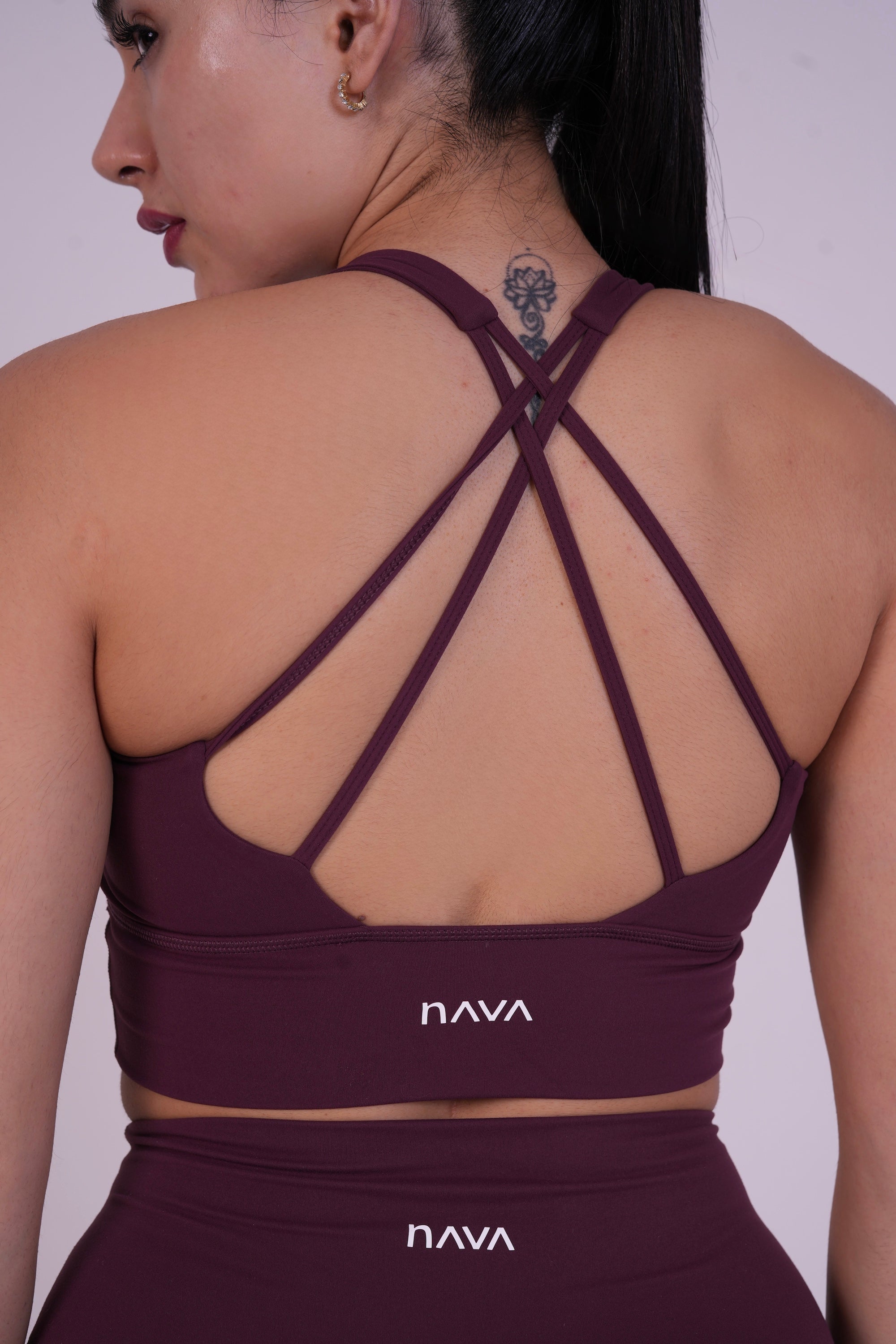 Back view of NAVA Dark Garnet yoga bra with cross-strap detailing and branded logo