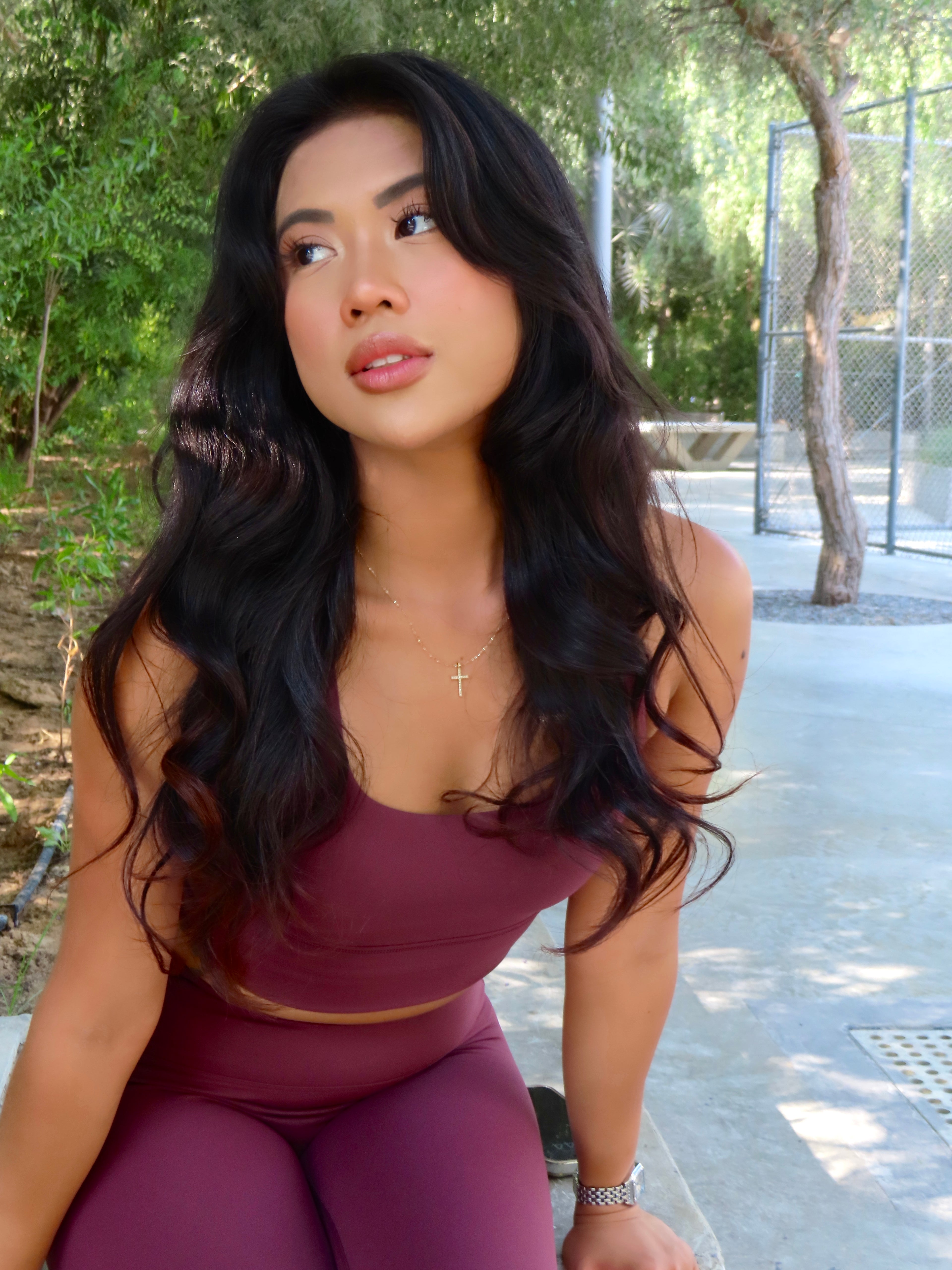 Model in NAVA Dark Garnet yoga set sitting outdoors in natural light, showing relaxed and confident look in activewear