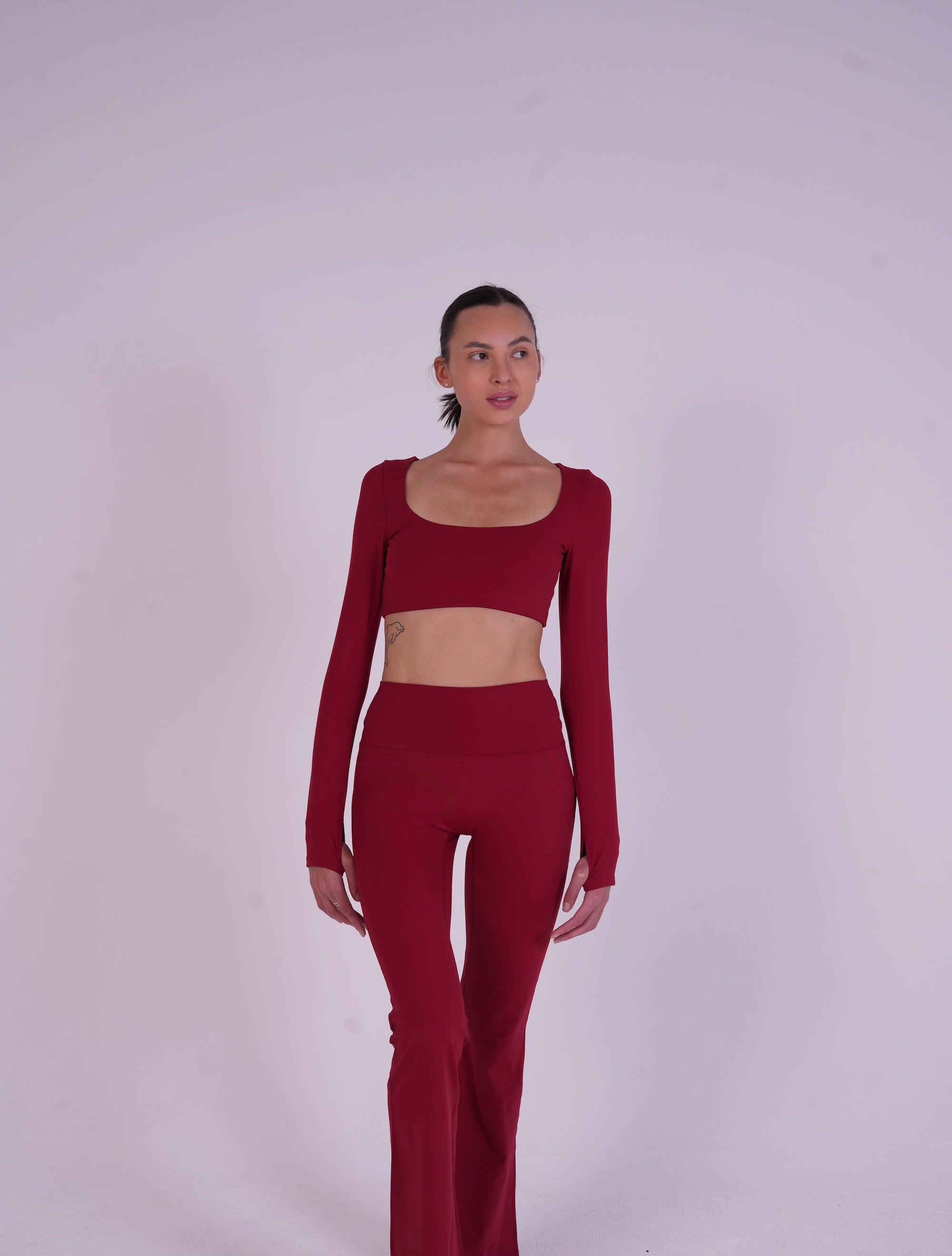 Front view of woman in NAVA Fire Opal full-set activewear, showcasing gemstone-inspired red yoga outfit designed for comfort and flexibility.
