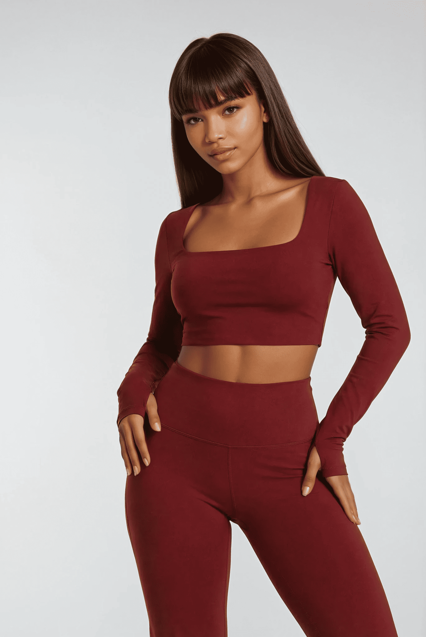 Woman wearing a burgundy long-sleeve top and leggings on a white background