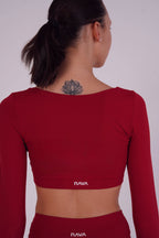 Person wearing a red long-sleeve crop top with 'NAVA' branding on a plain background