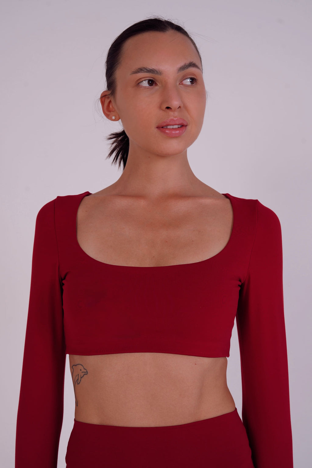 Woman wearing a red long-sleeve crop top against a plain background