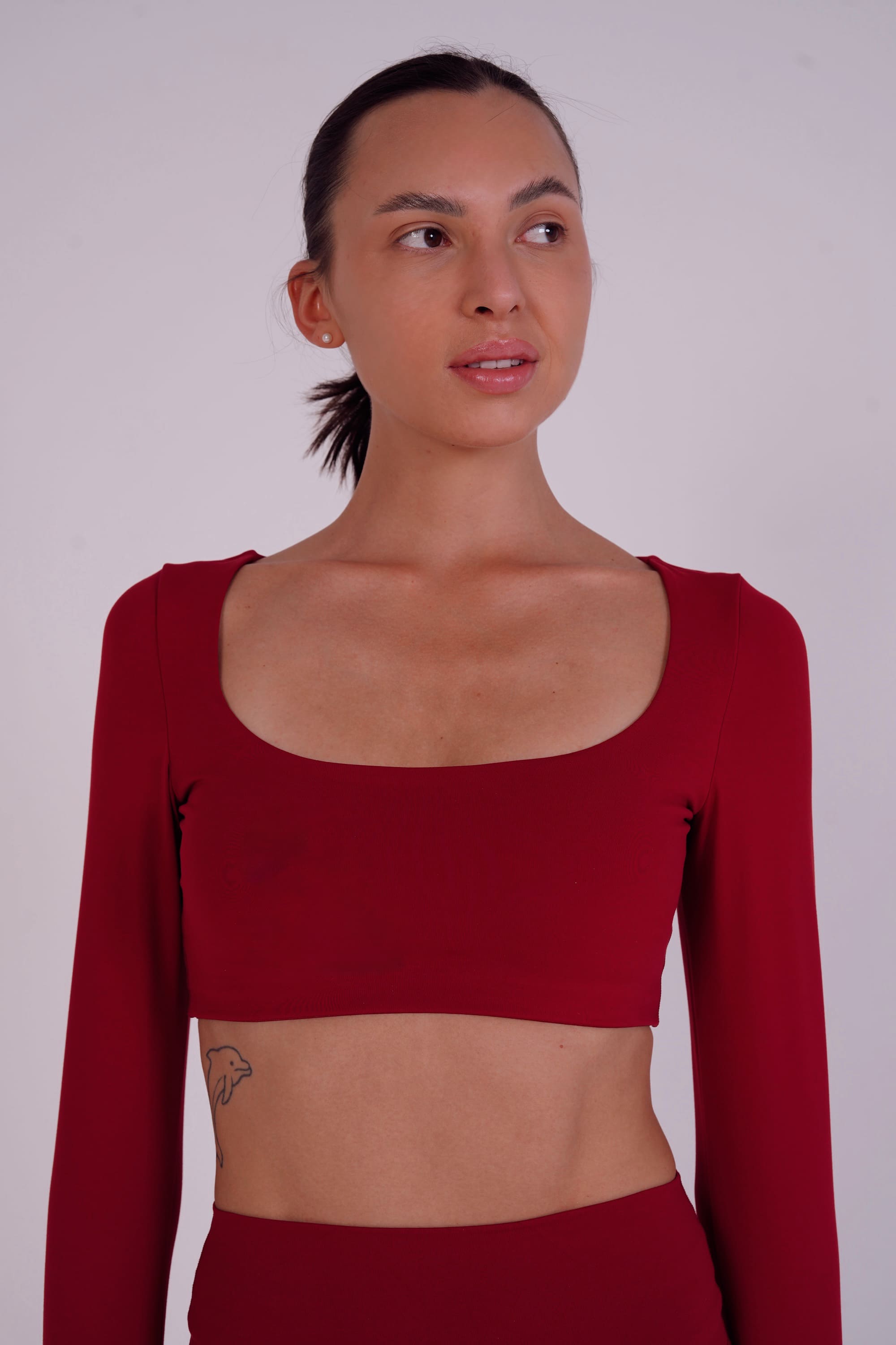 Woman wearing a red long-sleeve crop top against a plain background