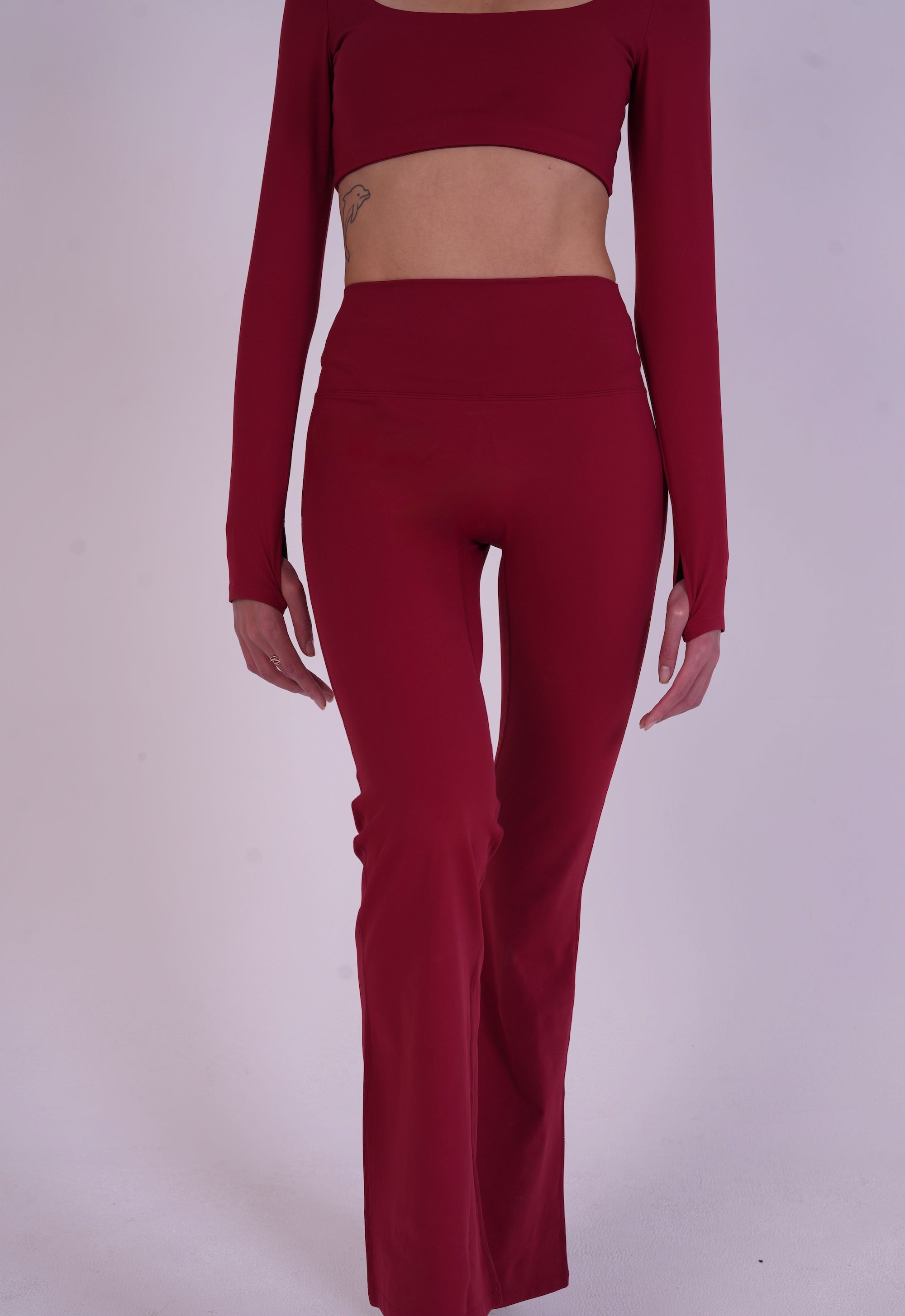 Front-side view of the NAVA Fire Opal leggings, featuring a gemstone-inspired red color and smooth, sculpting fit.