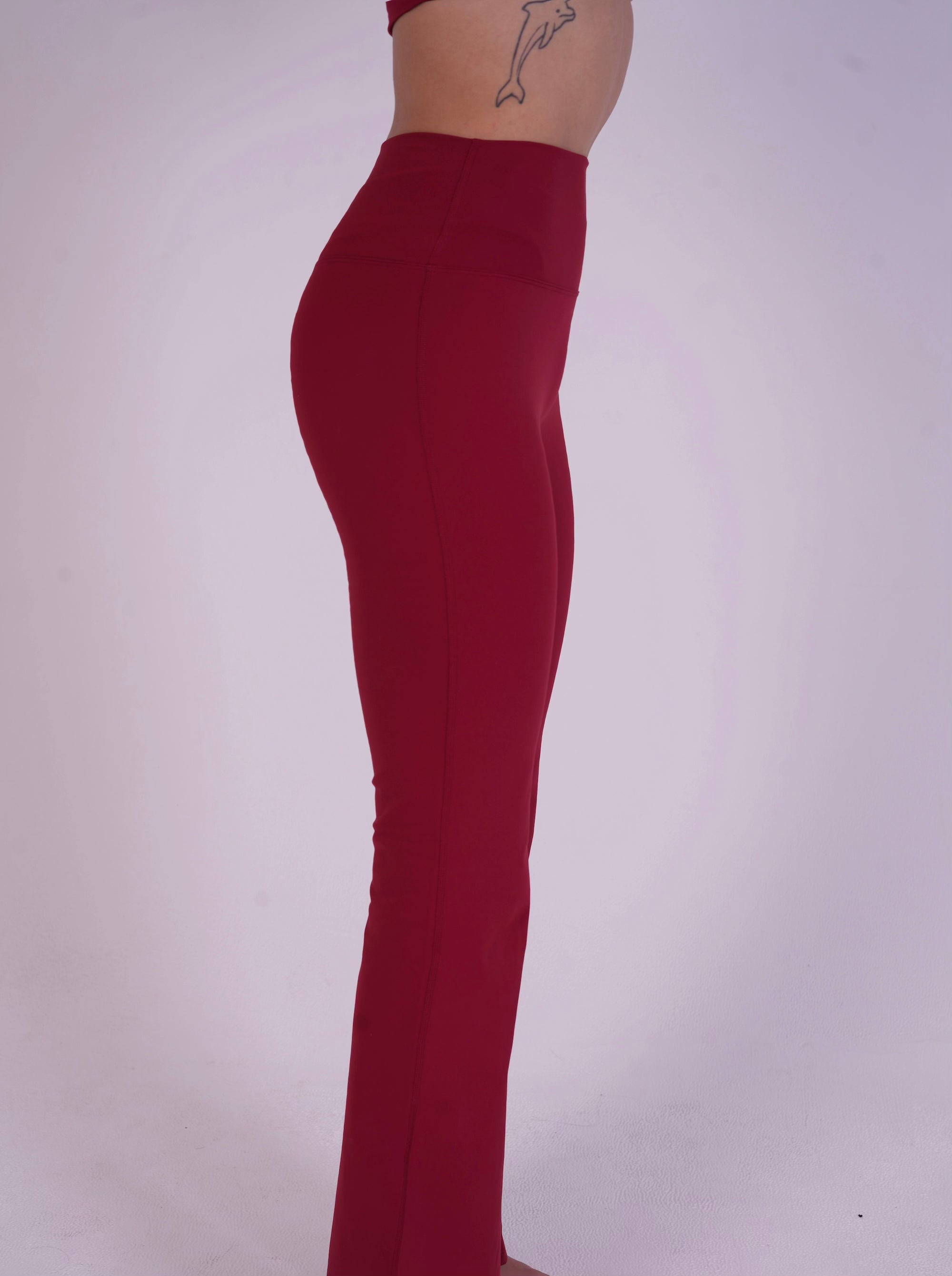 Side view of the NAVA Fire Opal leggings, highlighting the vibrant red gemstone color and smooth, sculpting fit.