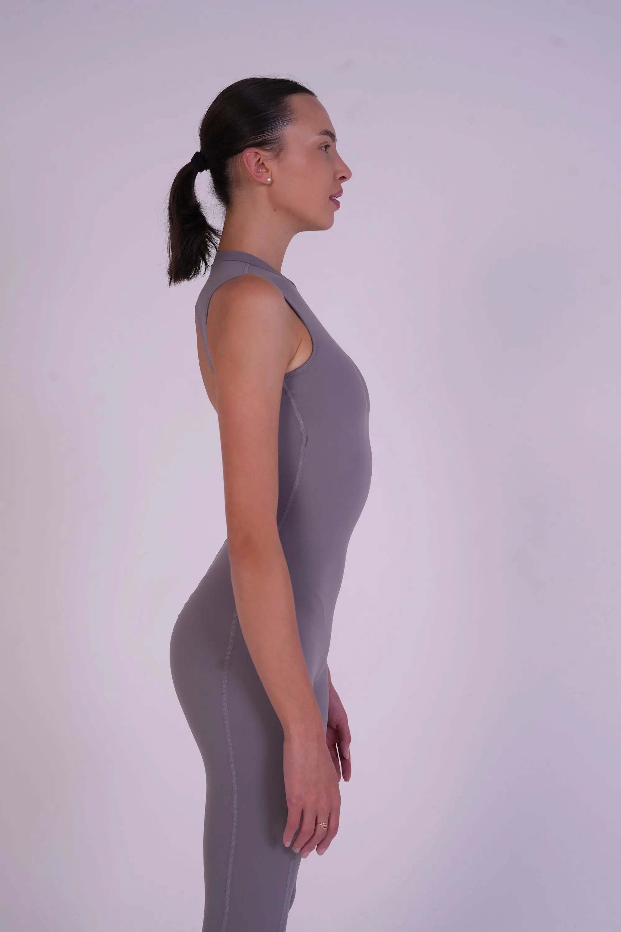 Side-angle full-body view of NAVA Grey Moonstone Jumpsuit highlighting the soft grey gemstone-inspired color, sculpting silhouette, and flexible activewear design.
