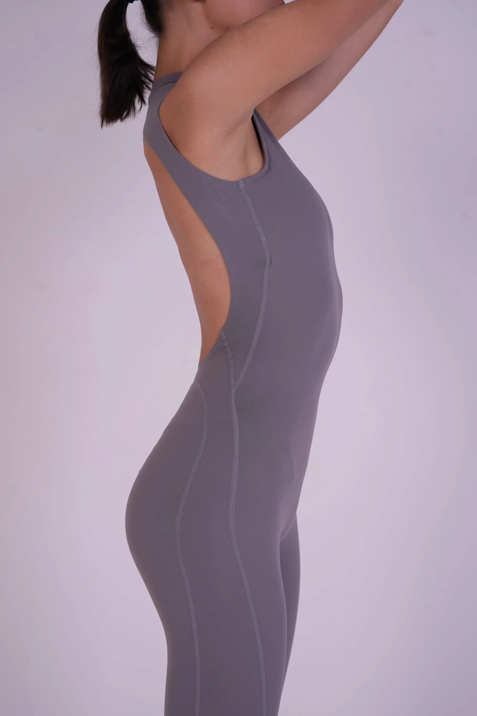 Side view of the NAVA Grey Moonstone Jumpsuit, highlighting the smooth grey gemstone tone and contouring full-body activewear design