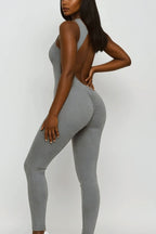 Woman wearing a gray open-back jumpsuit on a white background
