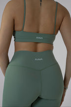 Person wearing green sports bra and leggings with 'Nava' branding on a plain background