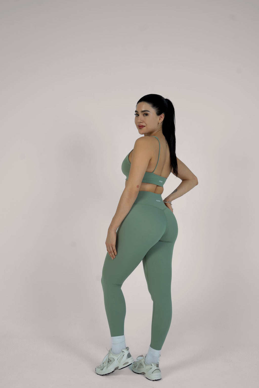 Woman wearing a green athletic outfit on a plain background