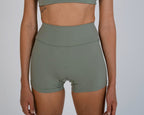 Person wearing green athletic shorts and crop top on a plain background