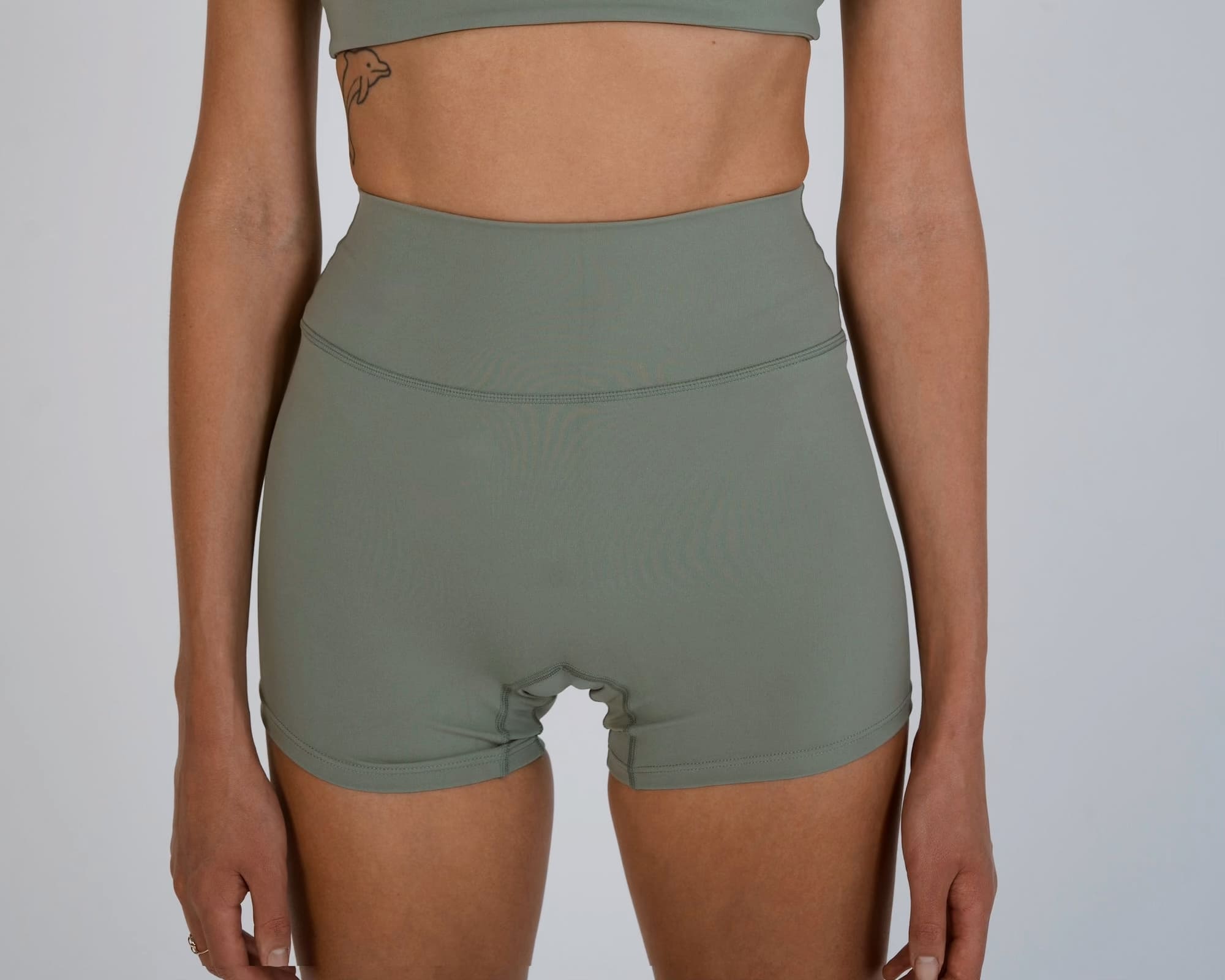 Person wearing green athletic shorts and crop top on a plain background
