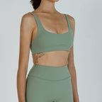 Person wearing a green sports bra and leggings set on a plain background