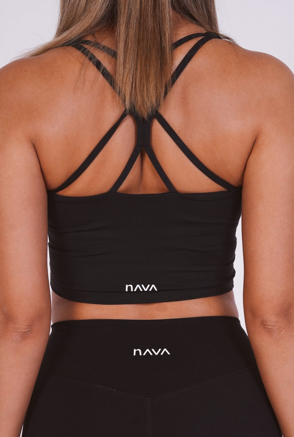 Black sports bra and leggings with 'NAVA' branding on a plain background