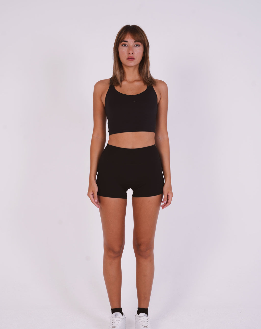 Woman wearing a black sports bra and shorts on a white background