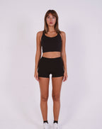 Woman wearing a black sports bra and shorts on a white background