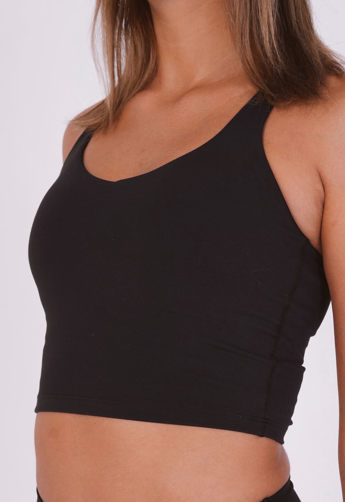 Black sports bra worn by a person on a white background