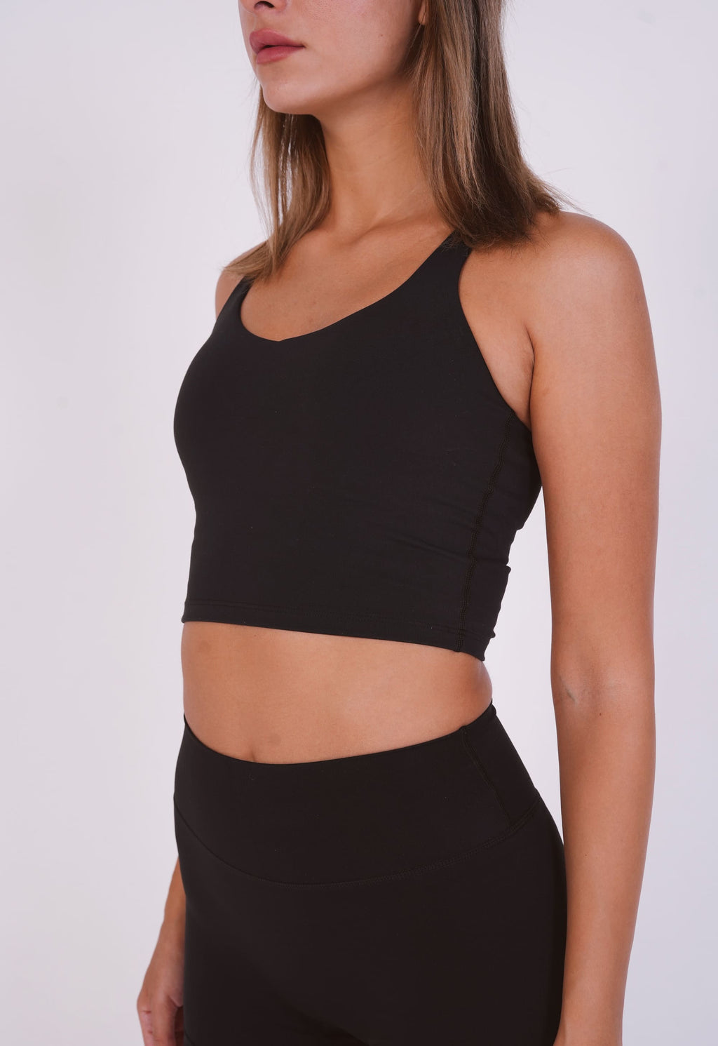 Person wearing a black sports bra and leggings on a white background