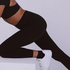 Person wearing black leggings and white sneakers on a light gray background