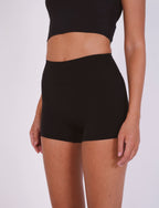 Person wearing black high-waisted shorts on a white background