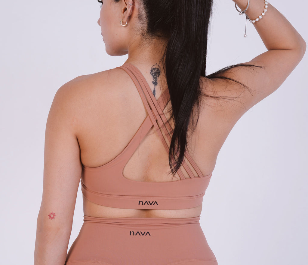 Person wearing a brown sports bra and leggings with 'Nava' branding on a light gray background