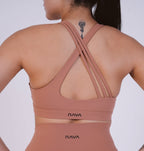 Person wearing a brown sports bra with 'NAVA' branding on a white background