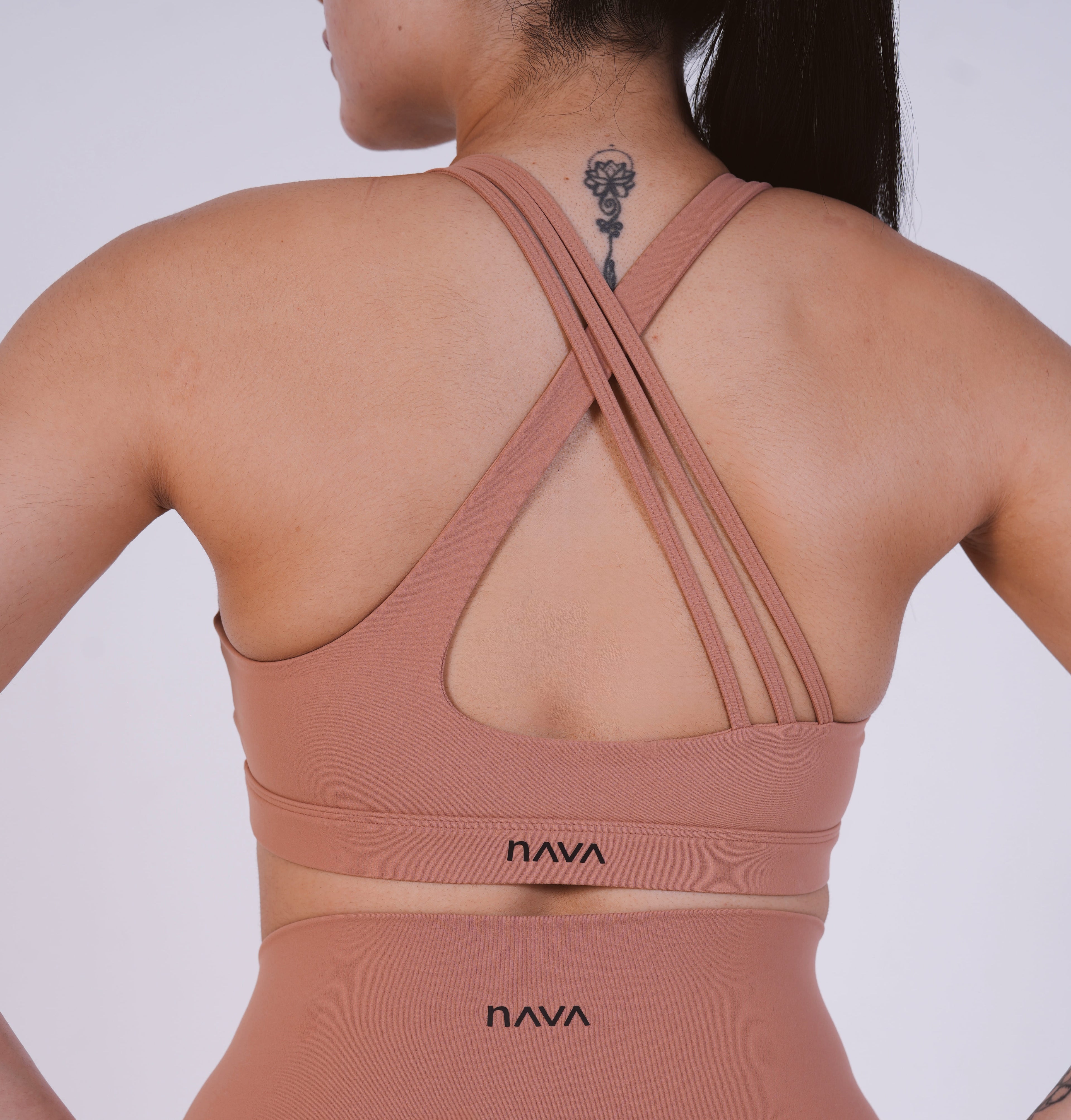 Person wearing a brown sports bra with 'NAVA' branding on a white background