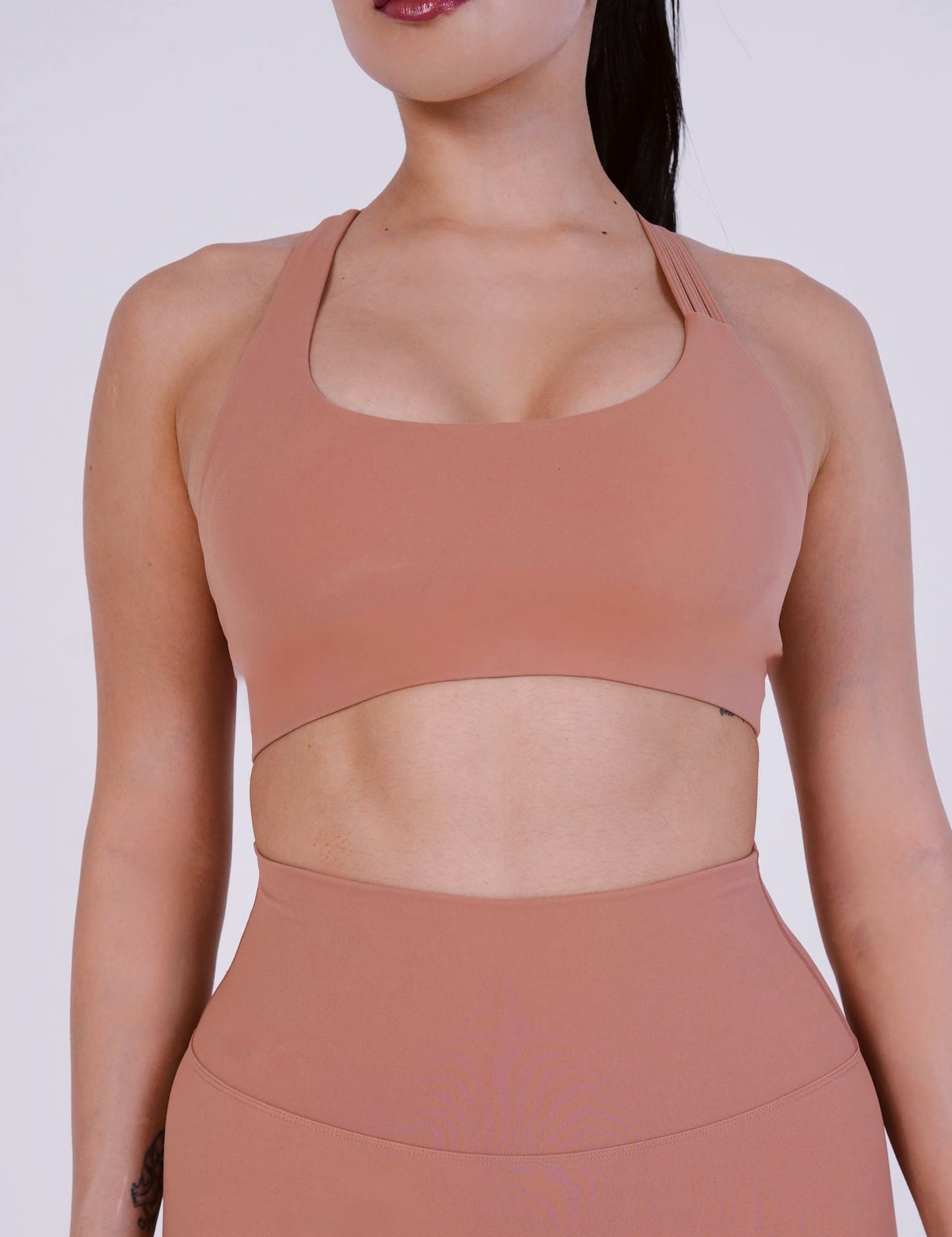 Person wearing a brown sports bra and leggings on a white background