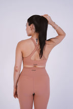 Woman wearing a pink sports bra and leggings set on a white background