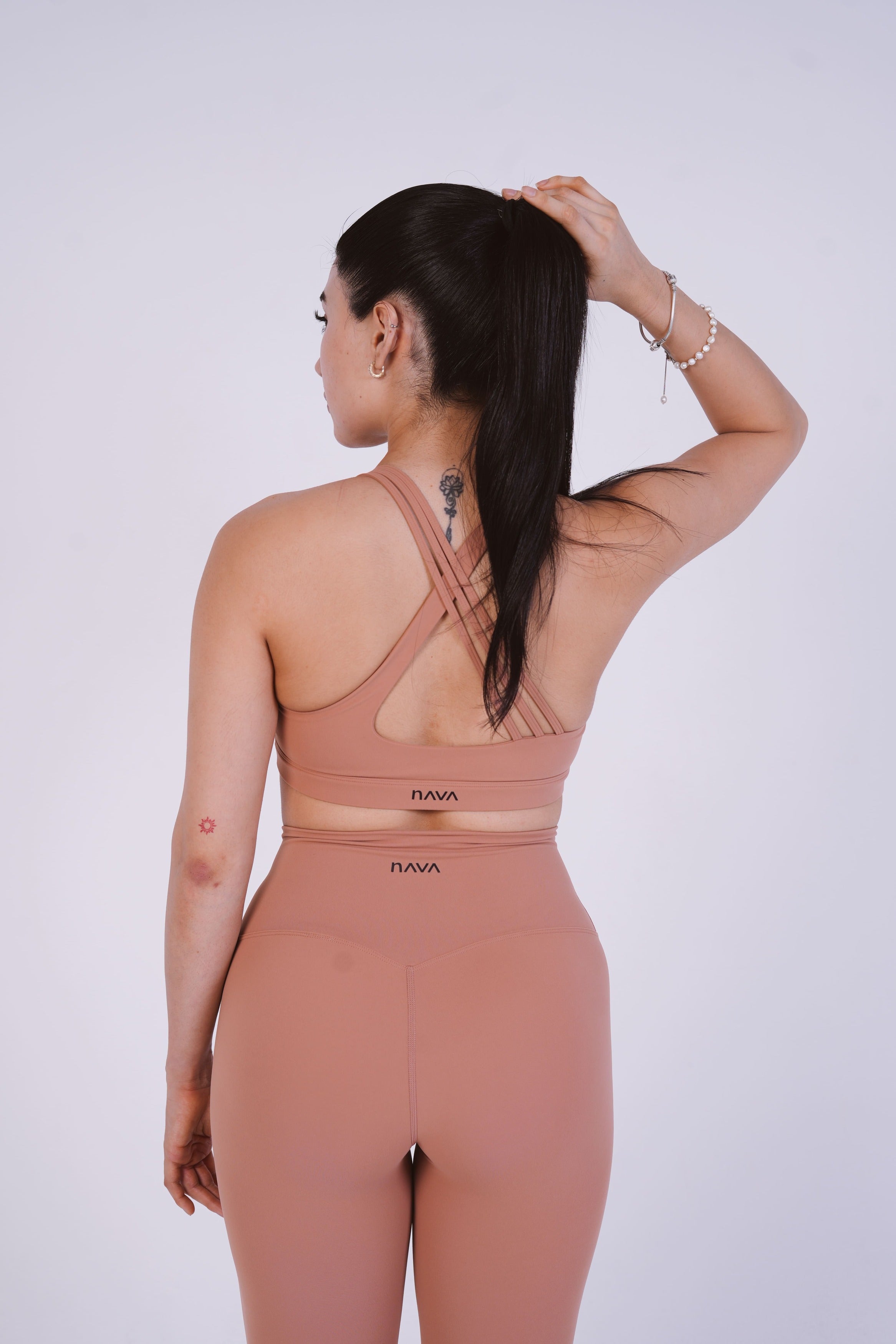 Woman wearing a pink sports bra and leggings set on a white background