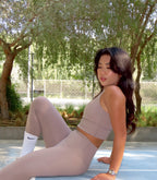 Woman in athletic wear sitting on a track with trees in the background