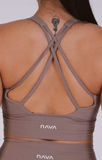 Brown sports bra with criss-cross straps and 'NAVA' branding on a white background