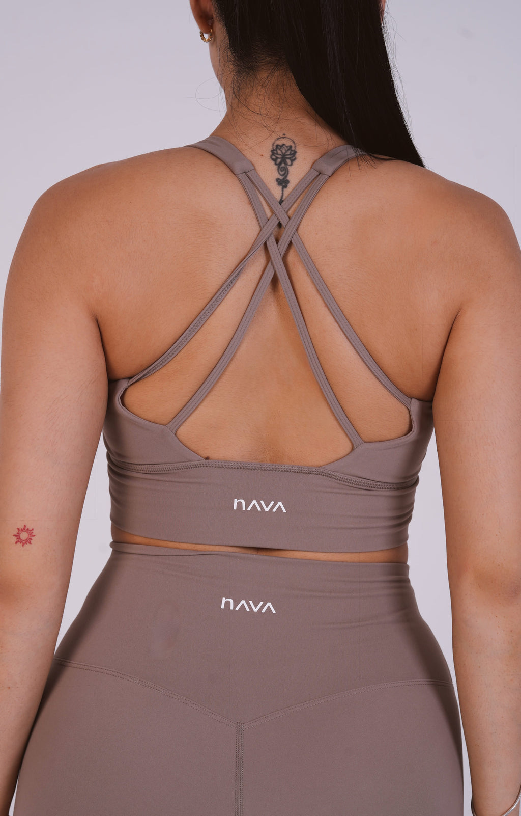 Person wearing a brown sports bra and leggings with 'Nava' branding on a plain background