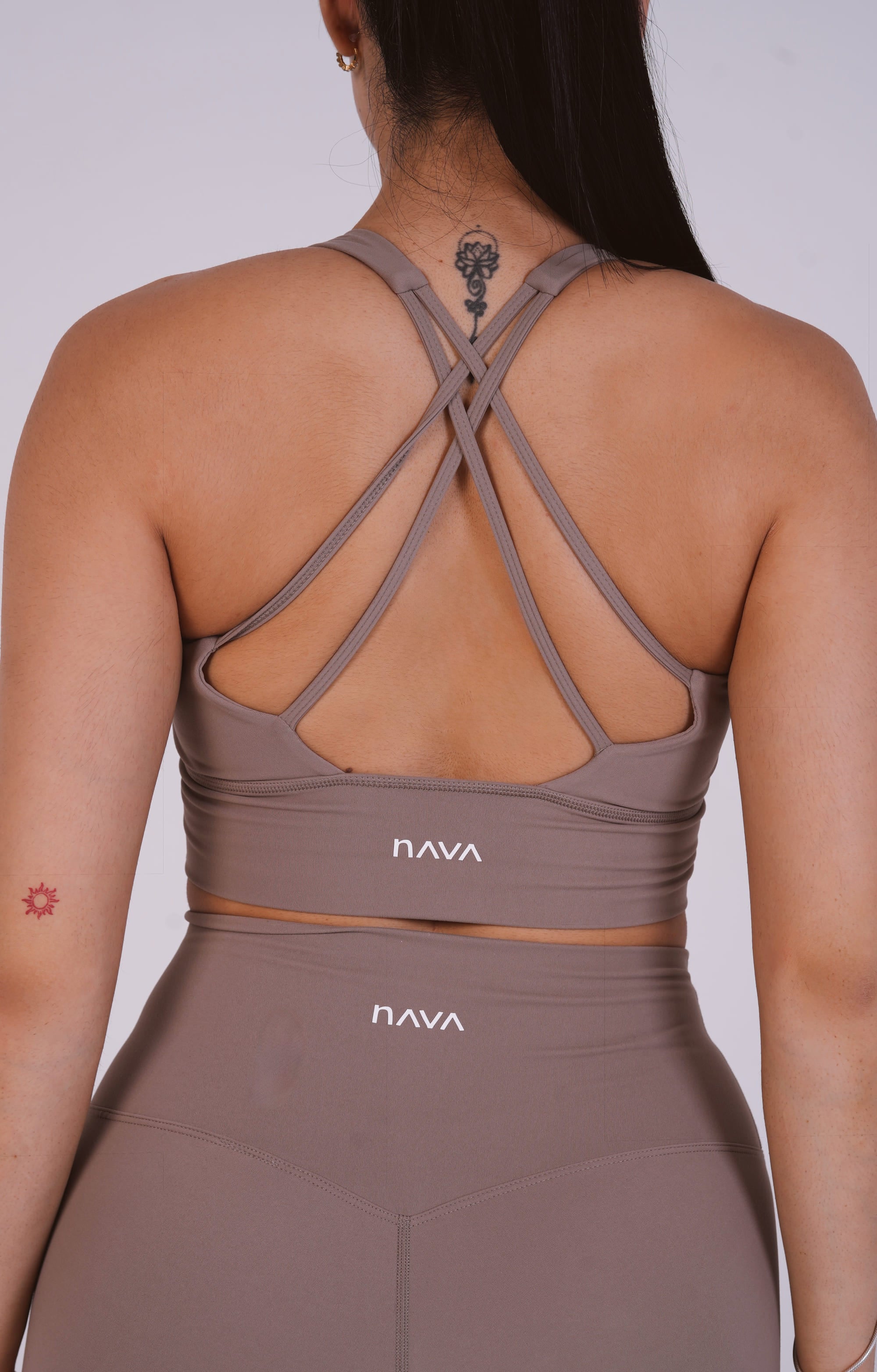 Person wearing a brown sports bra and leggings with 'Nava' branding on a plain background