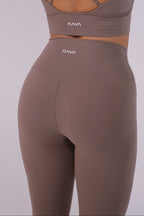 Brown sports bra and leggings set with 'NAVA' branding on a light gray background