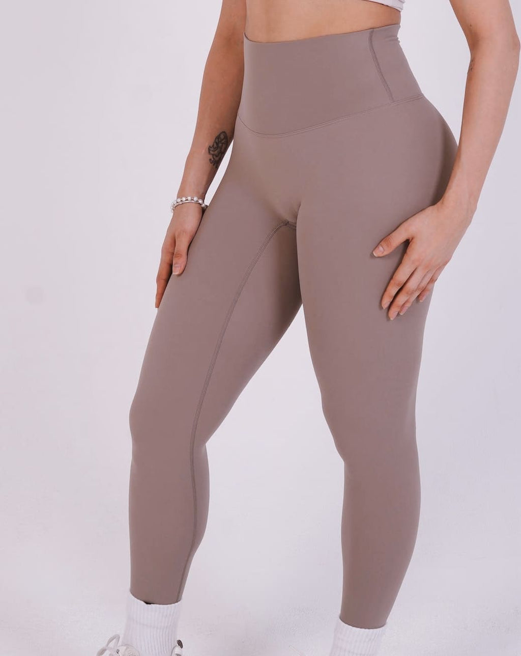 Person wearing brown leggings on a white background