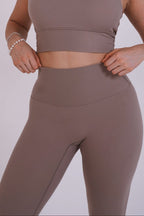 Person wearing a brown sports bra and leggings set on a light gray background