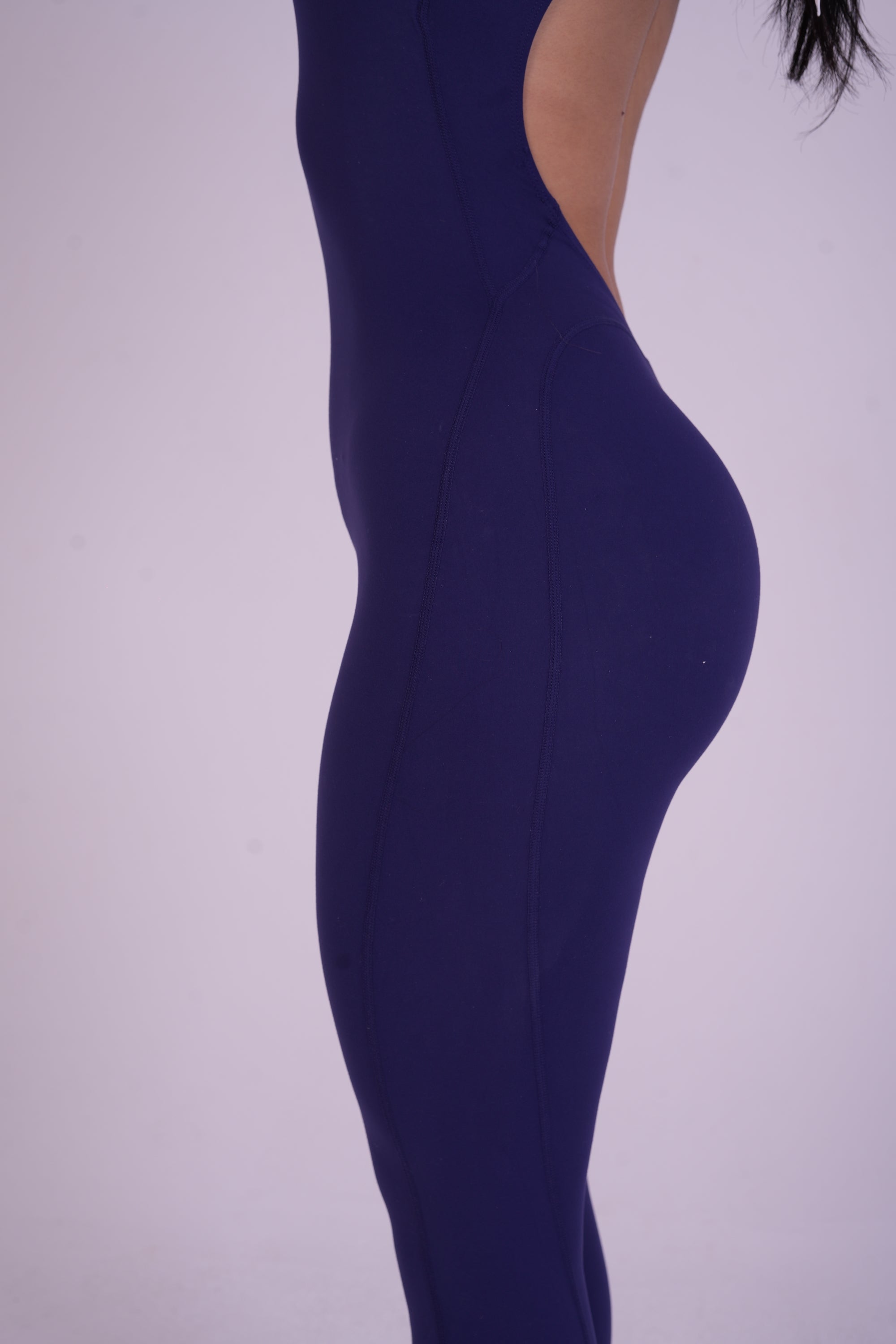 Side view of the NAVA Sapphire Jumpsuit, showcasing the deep blue gemstone tone and smooth, contouring full-body fit.