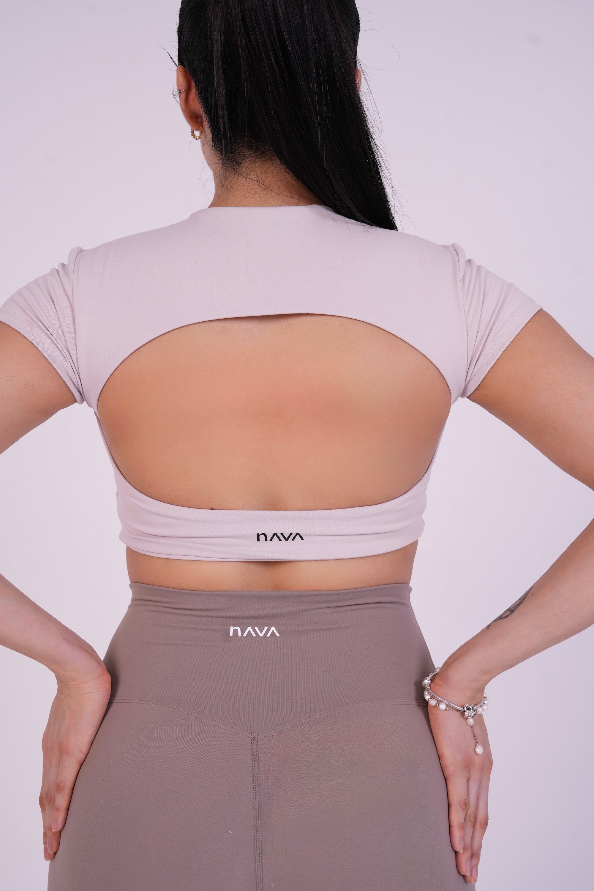 NAVA Smokey Quartz open-back crop top — back view on model, showcasing cutout design and soft neutral color.