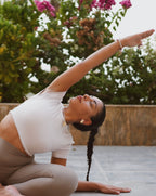 Woman practicing yoga outdoors with greenery in the background