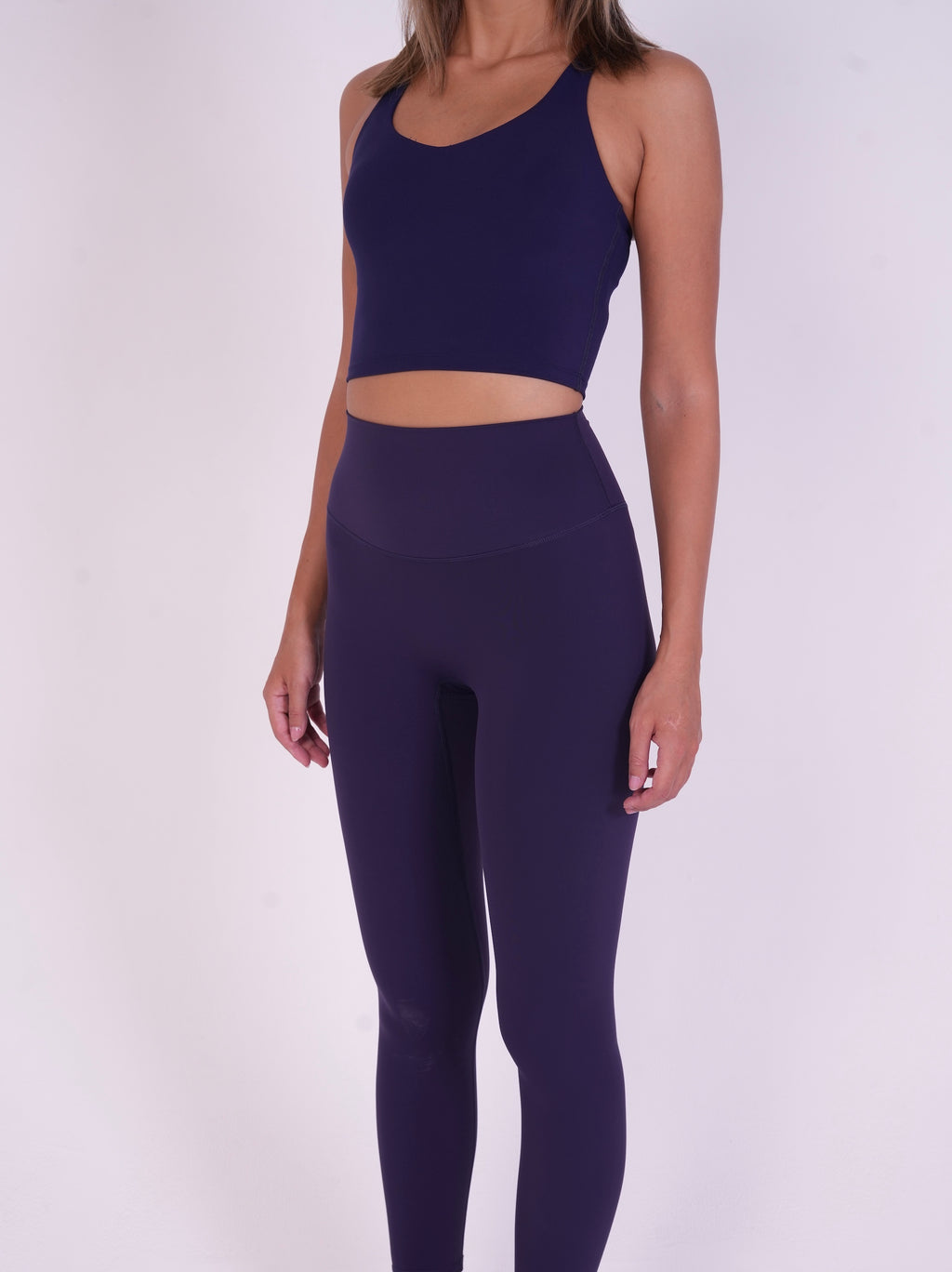 Woman wearing NAVA Sodalite Blue leggings and matching bra top, full-body view showcasing fit, color, and high-waist design.
